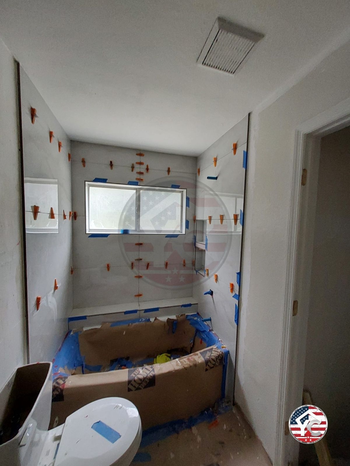 Tile installation in progress around a protected tub