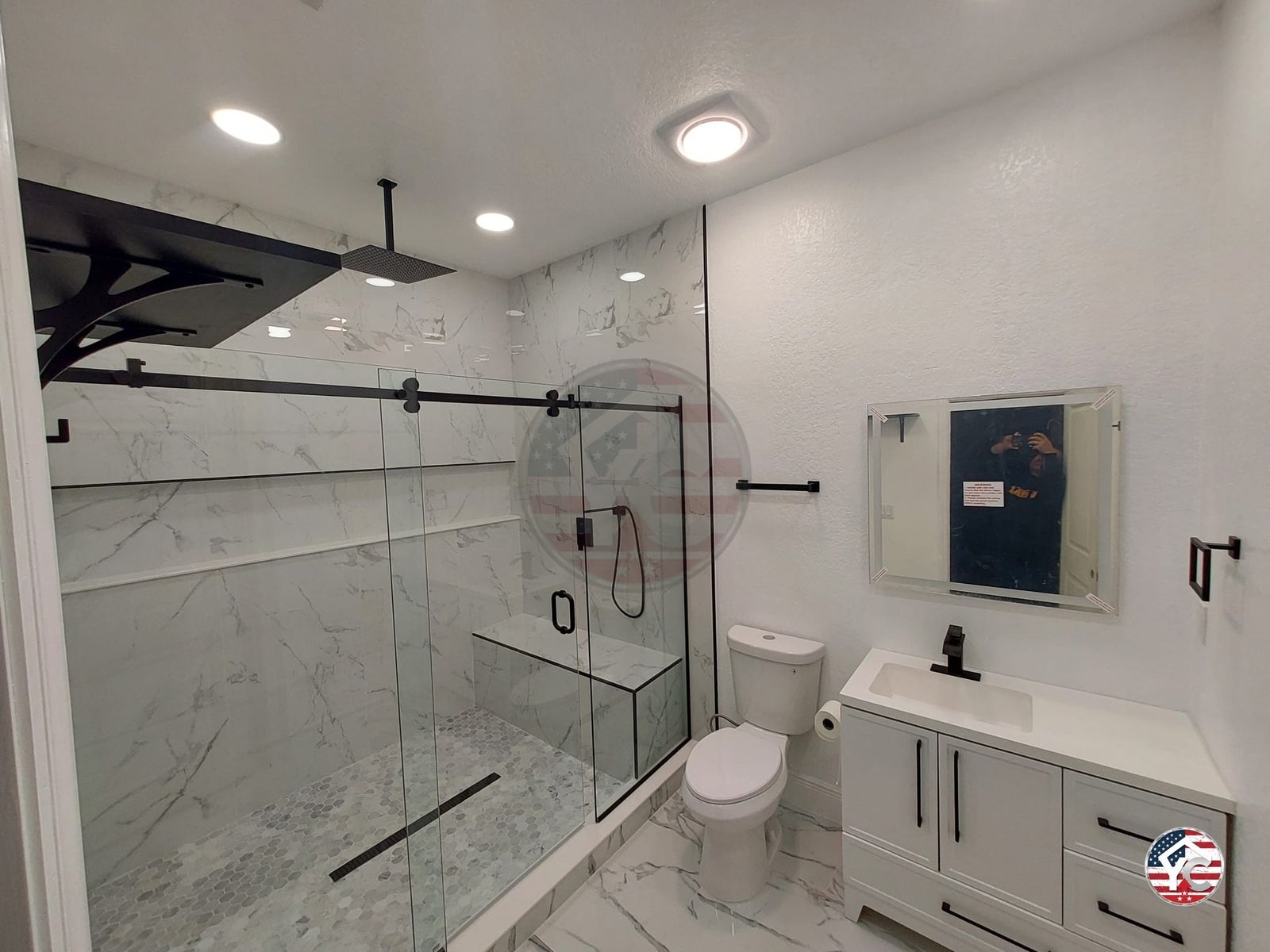 Rain shower head in marble tiled shower with bench